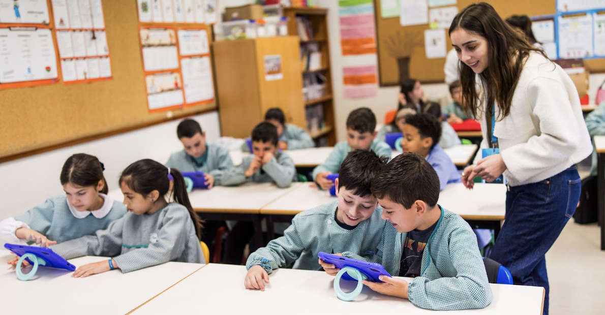 Junicoders: children in a classroom playing on tablets.